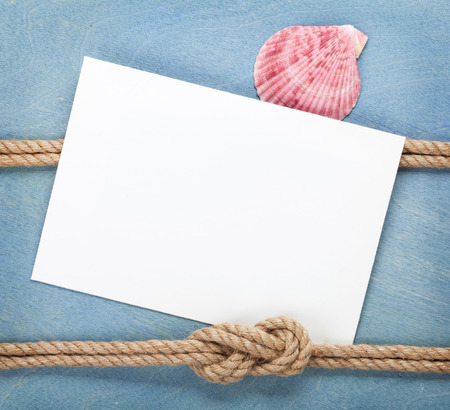 Blank paper card with ship rope over blue wooden backgroundの写真素材