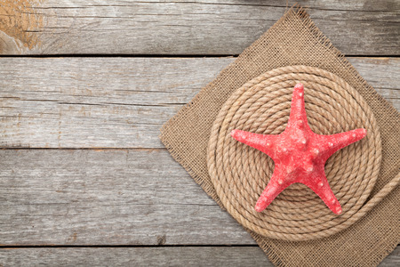 Starfish over ship rope and burlap on wooden background with copy spaceの写真素材