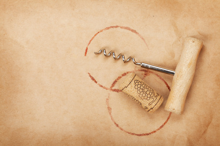 Corkscrew and cork with red wine stains on brown paper background with copy spaceの写真素材