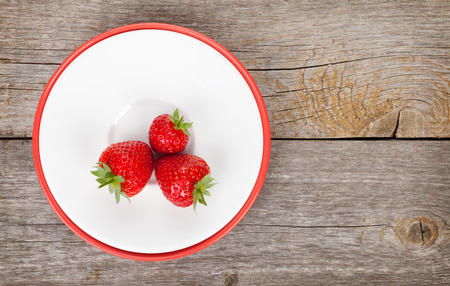 Plate with ripe strawberry over old wooden table background with copy spaceの写真素材