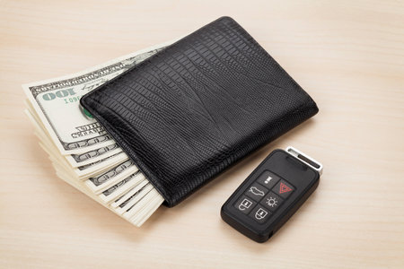 Money cash wallet and car remote key on wooden tableの写真素材