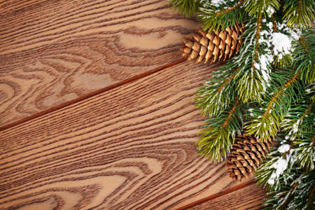 Christmas wooden background with snow fir tree and pinecones