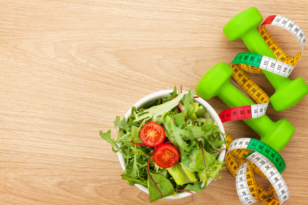 Dumbells, tape measure and healthy food over wooden background. Fitness and health. View from aboveの写真素材