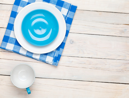 Empty plate, cup and towel over wooden table background. View from above with copy spaceの写真素材