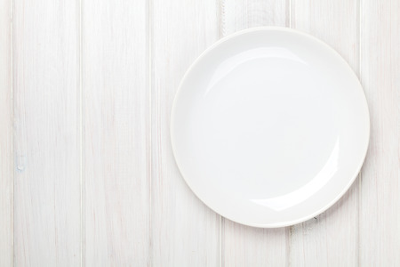 Empty plate over white wooden table background with copy spaceの写真素材