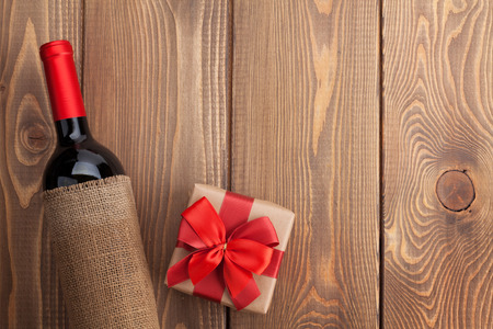 Red wine bottle and valentines day gift box. Over rustic wooden table background with copy spaceの写真素材