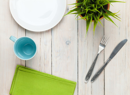 Empty plate, cup and silverware over white wooden table background. View from above with copy spaceの写真素材