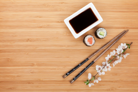 Maki sushi, chopsticks and soy sauce on bamboo wooden table background with copy spaceの写真素材