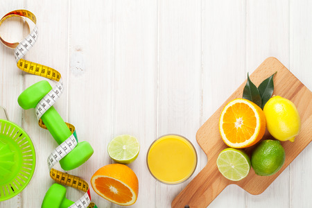 Citrus fruits, tape measure and dumbells. Oranges, limes and lemons. Healthy food. Over wood table background with copy spaceの写真素材