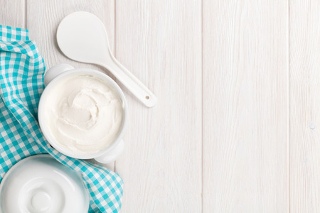 Sour cream in a bowl on wooden table. Top view with copy space