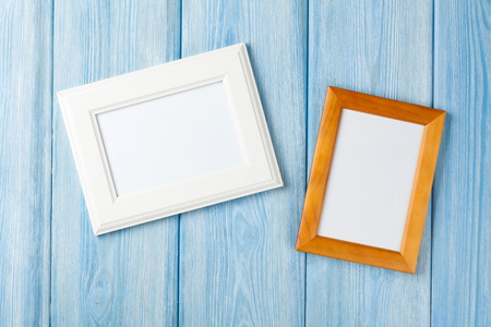 Photo frames on blue wooden wall with copy space