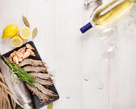 Fresh raw sea food with spices and whtie wine bottle on wooden table background. Top view with copy spaceの写真素材