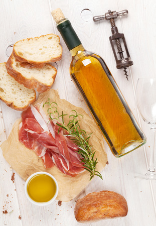 Prosciutto, wine, ciabatta, parmesan and olive oil on wooden table. Top viewの写真素材