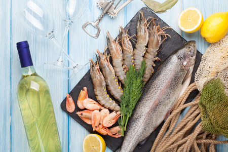 Fresh raw sea food with spices and whtie wine bottle on wooden table background. Top viewの写真素材