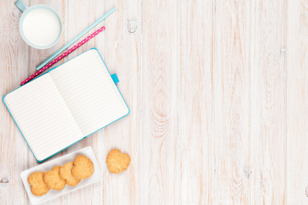 Cup of milk, heart shaped cookies and notepad on white wooden table with copy spaceの写真素材