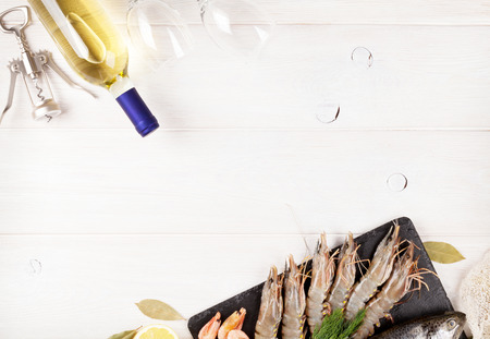 Fresh raw sea food with spices and white wine bottle on wooden table background. Top view with copy spaceの写真素材