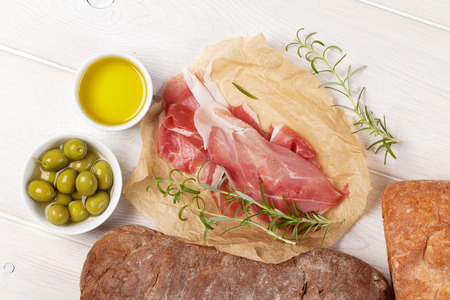 Italian prosciutto with ciabatta and olives on white wooden tableの写真素材