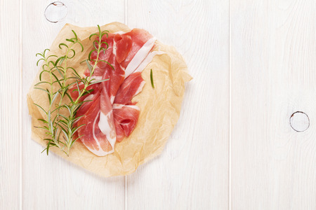 Prosciutto with rosemary on wooden table. Top view with copy spaceの写真素材