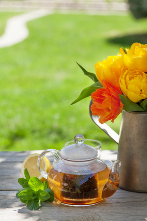 Breakfast tea on garden table and colorful tulips bouquetの写真素材