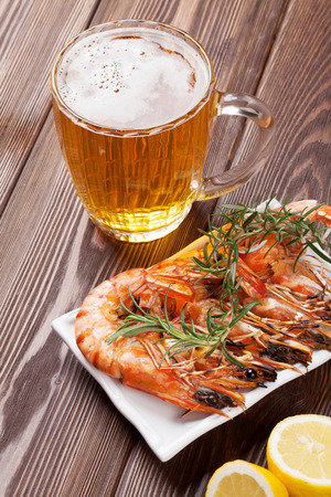 Beer mug and grilled shrimps on wooden tableの写真素材