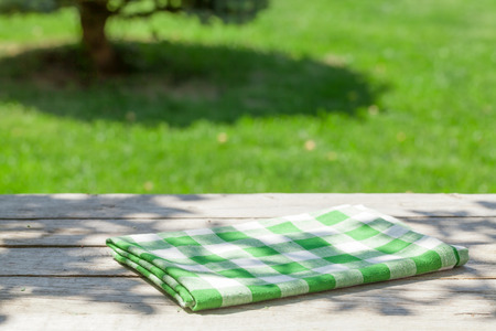 Empty wooden garden table with tablecloth with green bokeh backgroundの写真素材
