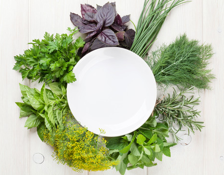 Fresh garden herbs and empty plate on wooden table. Top view with copy spaceの写真素材