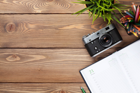 Office desk table with camera, supplies and flower. Top view with copy spaceの写真素材