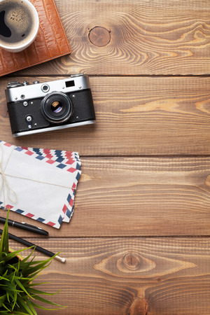 Camera and supplies on office wooden desk table. Top view with copy spaceの写真素材