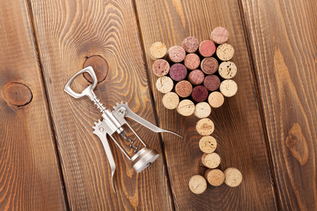 Glass shaped corks and corkscrew. View from above over rustic wooden table backgroundの写真素材