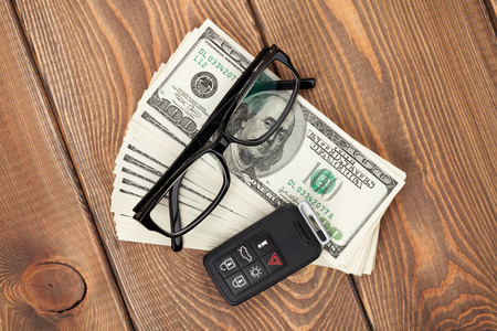 Money cash, glasses and car remote key on wooden tableの写真素材