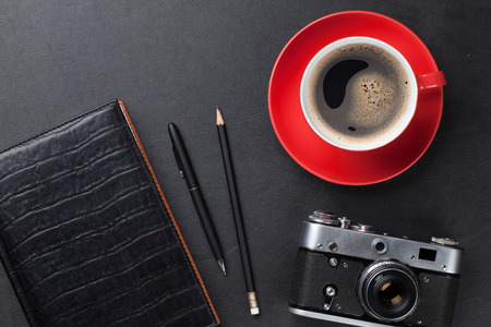 Office leather desk table with camera, supplies and coffee cup. Top view
