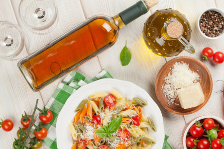Colorful penne pasta and white wine on wooden table. Top viewの写真素材
