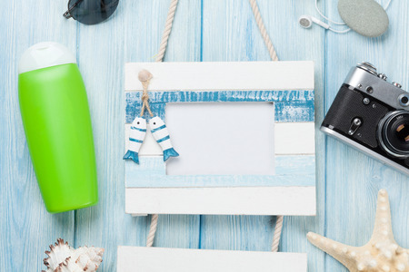 Travel and vacation photo frame and items on wooden table. Top viewの写真素材