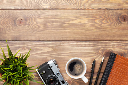 Camera and supplies on office wooden desk table. Top view with copy spaceの写真素材
