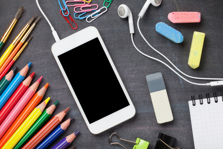 School, office supplies and smartphone on blackboard background.  の写真素材