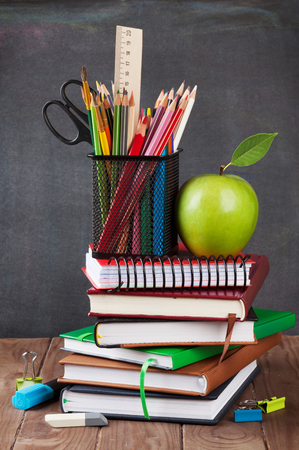 School and office supplies on classroom table in front of blackboardの写真素材