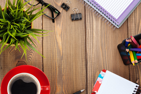 Office table with flower, blank notepad and coffee cup. View from above with copy spaceの写真素材