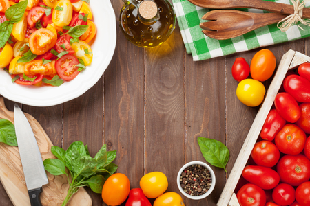 Fresh colorful tomatoes and basil salad on wooden table. Top view with copy spaceの写真素材