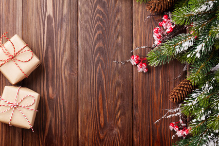 Christmas wooden background with snow fir tree and gift boxesの写真素材