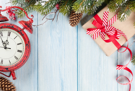 Christmas wooden background with snow fir tree, alarm clock and gift boxの写真素材