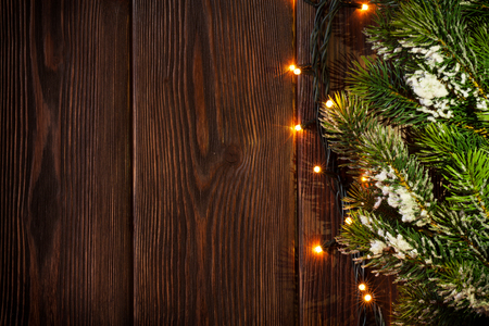 Christmas tree branch and lights on wooden background. View with copy spaceの写真素材