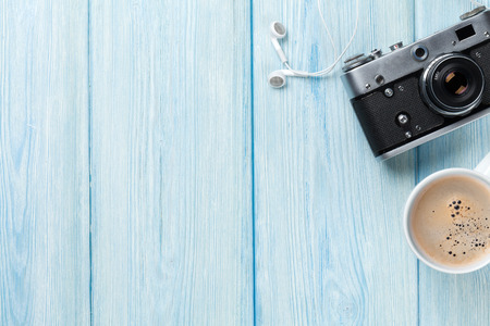 Travel camera and coffee cup on wooden table. Top view with copy spaceの写真素材