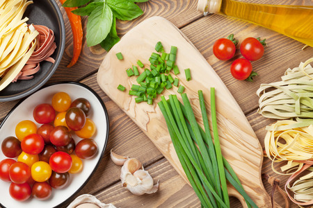 Pasta cooking ingredients and utensils on wooden table. Top view