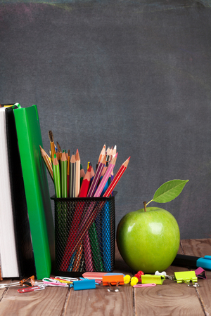 School and office supplies on classroom table in front of blackboard. View with copy spaceの写真素材