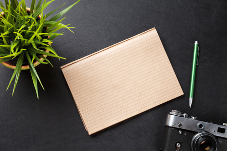 Office leather desk table with camera, supplies and flower. Top view with copy spaceの写真素材
