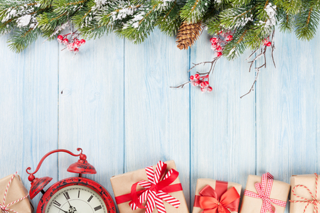 Christmas wooden background with snow fir tree, alarm clock and gift boxes. View with copy spaceの写真素材