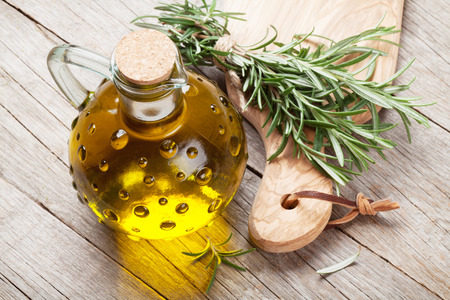 Fresh garden rosemary and olive oil on wooden tableの写真素材