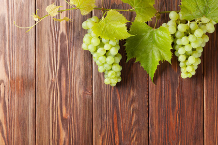 Bunch of white grapes with leaves on wooden background with copy spaceの写真素材