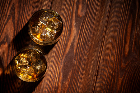 Glasses of whiskey with ice on wooden table. Top view with copy space Glasses of whiskey with ice on wooden table. Top view with copy space