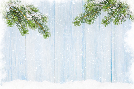 Christmas fir tree in snow in front of wooden wall. View with copy spaceの写真素材